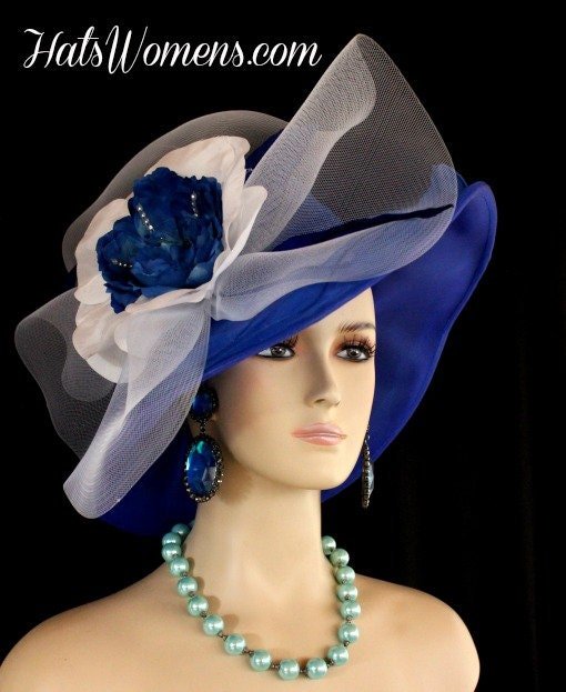 Ladies Haute Couture Royal Blue And White Lightweight Chiffon Wide Brimmed Designer Special Occasion Fashion Couture Hat. This Formal Dress Hat Is Trimmed With A Large White Crinoline Bow, Accented With A Hand Made Royal Blue And White Silk Flower, Trimmed With Rhinestones. Expensive Hand Made Royal Blue Leaf Petals Are Placed Around The Flower. This Is A Stunning Hat For The Spring Horse Races, The Kentucky Derby, The Belmont Stakes, The Preakness Stakes, The Royal Ascot, The Melbourne Cup, And The Royal Ascot.