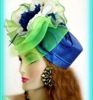 Royal Blue And Lime Green Fancy Pillbox Designer Cocktail Hat For Women. This Dress Hat Is Suited For Winter, Spring, Summer Or Fall. This pillbox hat is embellished with a large lime green ornate bow, adorned with ivory and royal blue flowers. Delicate, royal blue feathers, give this hat such elegance. A Perfect Special Occasion Hat, To Wear To Church, A Wedding, Formals, Cocktail Parties, Tea Parties, Holiday's, Horse Races, The Kentucky Derby, The Belmont Stakes, The Preakness, And Polo Matches. Custom Made And Designed By NY Fashion Hats, www.nyfashionhats.com