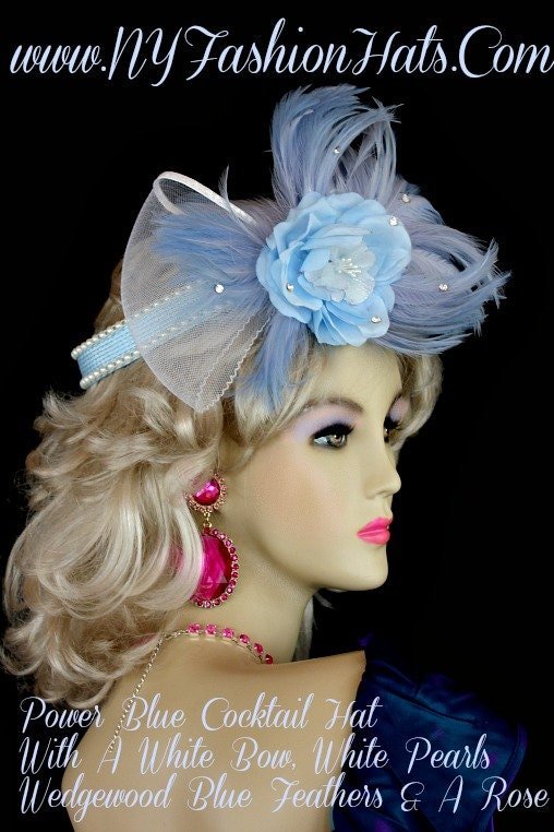 Women's Pastel Sky Baby Blue And White Custom Made Cocktail Hat, Wedding Fascinator, Flower Halo, Crown Half Hat, With A Custom Made Blue Silk Flower. Beautiful Wedgewood Blue Feathers, Are Placed With The Large White Sheer Netting Bow. Glass Rhinestones, Give This Headpiece Such Style. This Hair Accessory Hat, Can Be Worn Like A 1920' Flapper Hat. Also Suited For Art Deco Parties. This Formal Brides Headpiece, Is Suited For Winter, Spring, Summer Or Fall. We Specialize In Cocktail Hats For Women, Pillbox Hats With Veils, Wedding Fascinators, Hats With Feathers, Satin Dress Hats For Women, Hairband Hats, Bridal Headpieces, Hats For Brides, Hair Accessories For Women, Custom Designer Hats, Kentucky Derby Hats, Hats For Horse Races, Hats For Formals, Church Hats, And Special Occasion Hats. Custom Made And Designed By NY Fashion Hats Custom Millinery Headwear. https://www.nyfashionhats.com