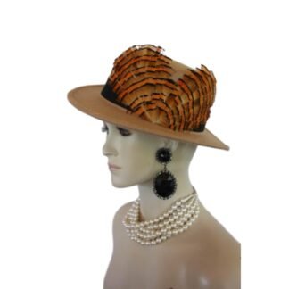 Step into the realm of haute couture with the Ladies Camel Beige Gondola Bolero Gaucho Designer Hat—a true masterpiece that embodies the elegance and sophistication of high fashion. This striking boater-style hat, meticulously crafted by the renowned artisans at NYFashionHats.com, showcases an exquisite blend of sumptuous multi-colored orange, beige, and black duck feathers. Its daring design redefines what it means to make a fashion statement, ensuring that all eyes are on you at every occasion.
